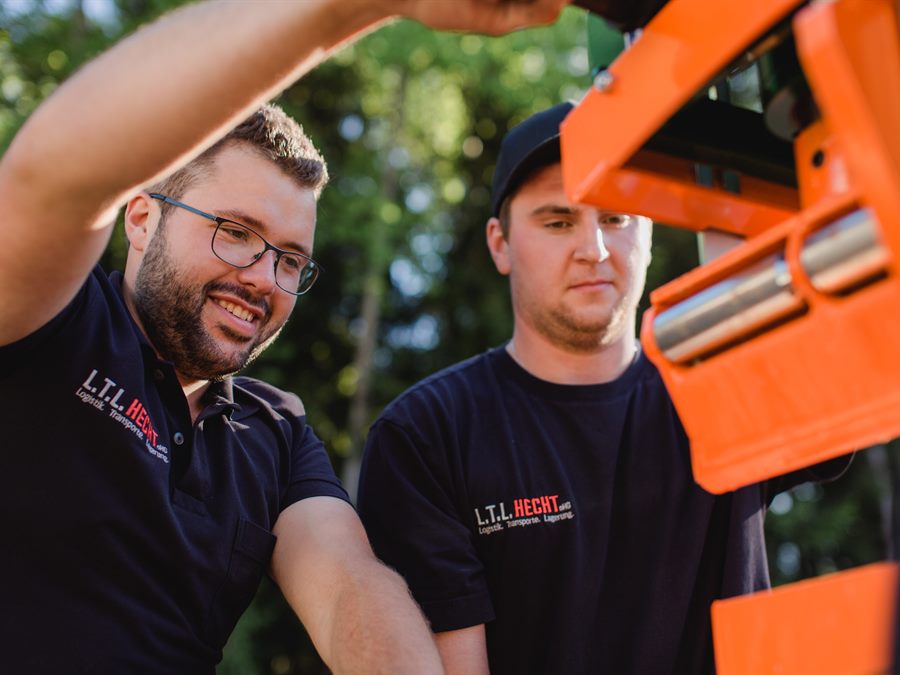 Zwei Mitarbeiter der Holzbrikettfarm besprechen sich an einer Maschine